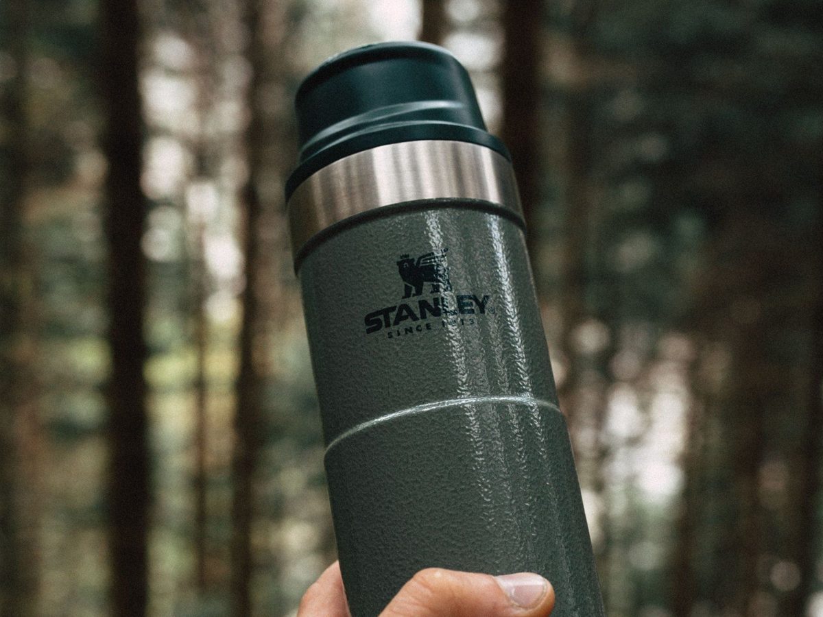 An insulated bottle held in a forest