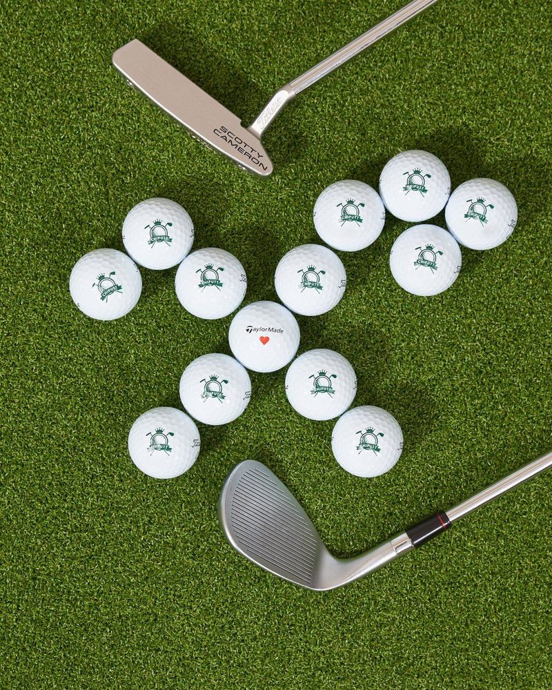 Logo golf balls on turf with a putter and a wedge