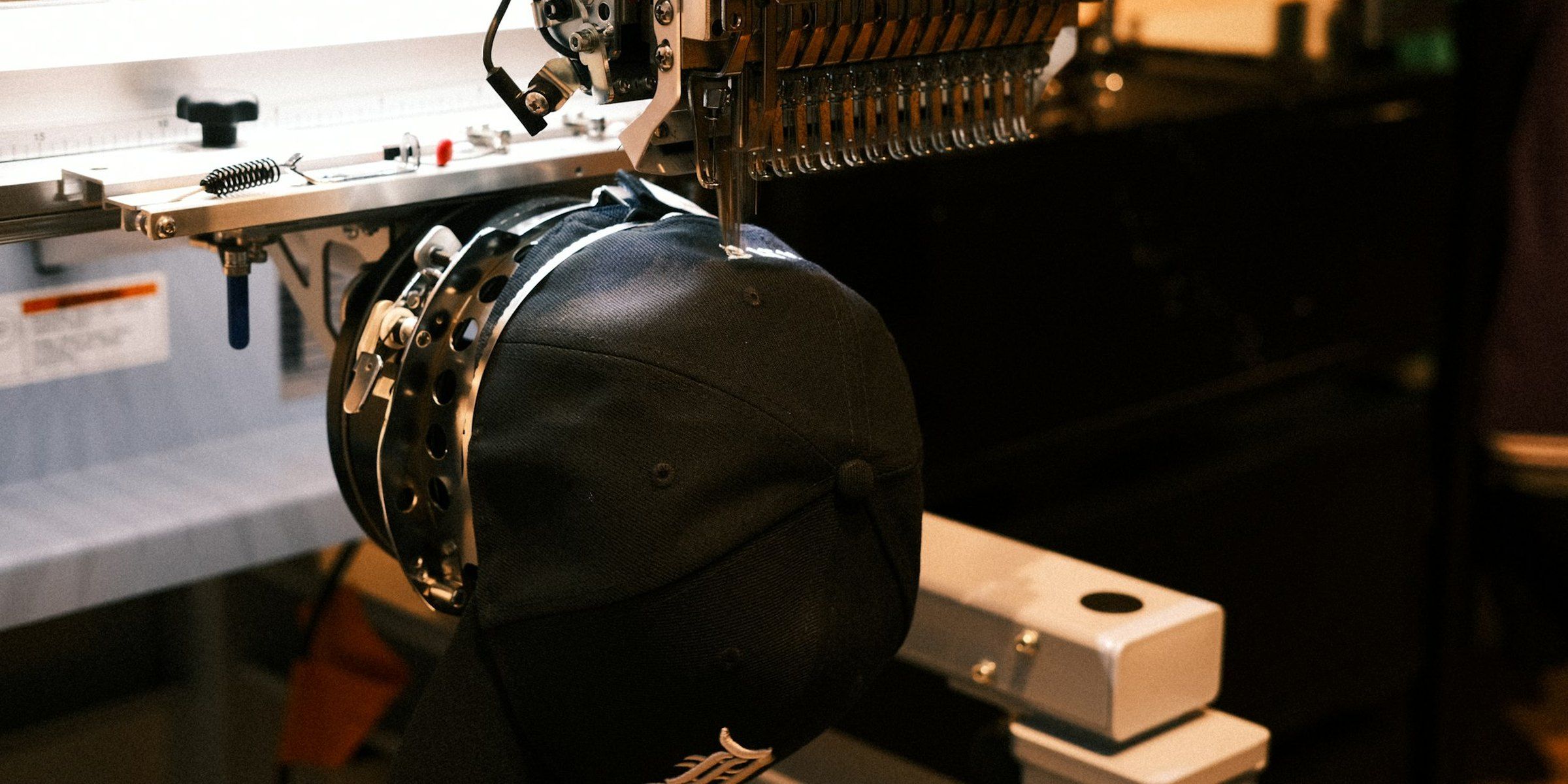 An embroidery machine stitching a logo onto a cap
