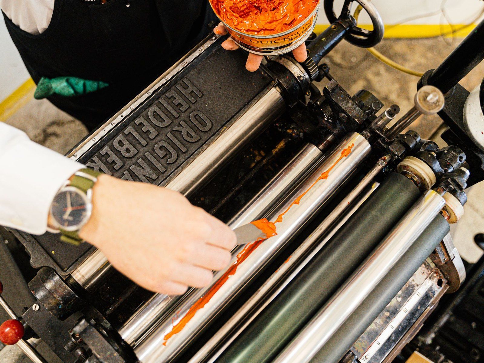 Hands working ink across a printing press