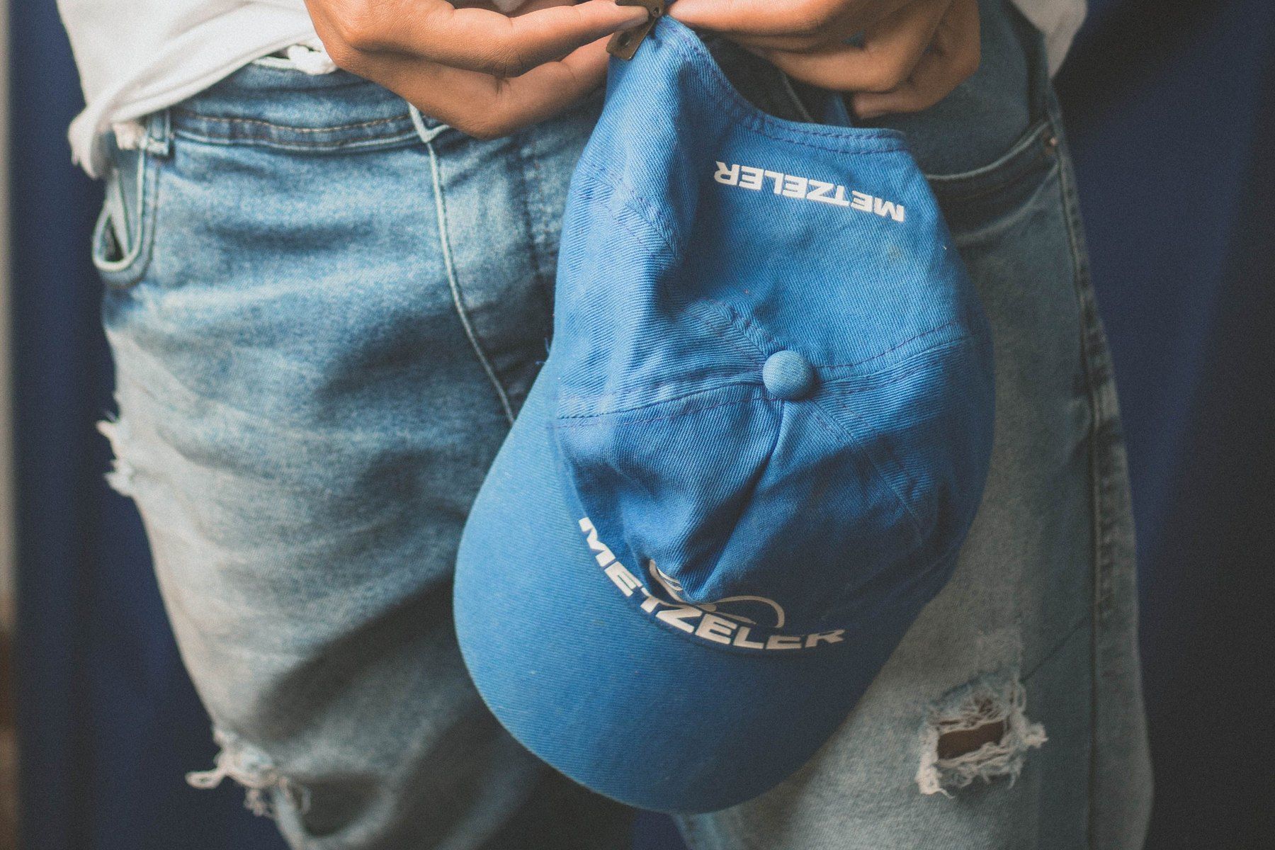 A person holding a worn cap